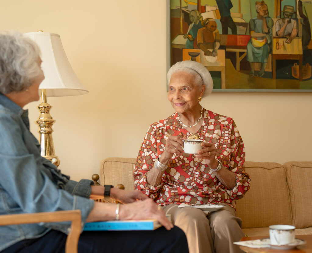 Two women sitting down in conversation while drinking tea.